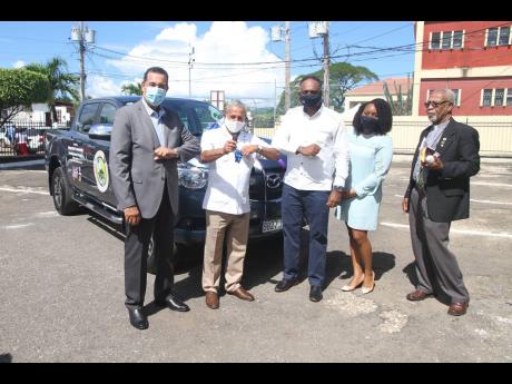 Councillor Winston Maragh (second left), mayor of May Pen, accepts the keys to a 4X4 Double Cab Pickup from Omar Sweeney (centre), managing director of the Jamaica Social Investment Fund (JSIF), during the handover ceremony of equipment and a motor vechile
