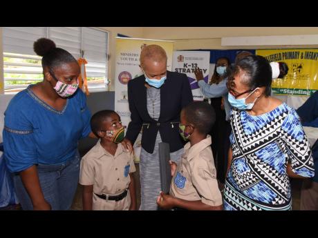 Minister of Education, Youth and Information Fayval Williams (centre) converses with students of Bellefield Primary and Infant School in Manchester, six-year-old Jayden Perron (second left), and 10-year-old Terone Thompson, following a ceremony at the inst