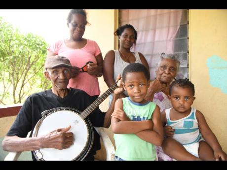 Cyril Dixon (left), 101 years old, plays his guitar and sings a song for his family: wife Olga Dixon (seated right), daughter  Mervis Dixon (standing left), and great-grandchildren Kellyshae Tomlinson (standing right) and Mykale Simpson (centre), and great
