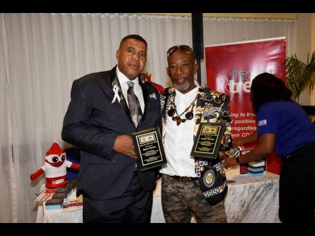 Wayne Bartley (left) and Audley Malcolm shows off their Outstanding Father Awards received at the International Men’s Day Observance and Celebration Forum 2020 at The Jamaica Pegasus Hotel in New Kingston yesterday.