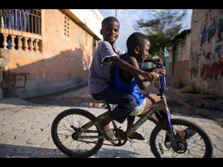 
Friends share a bicycle through the Cite Soleil slum of Port-au-Prince, Haiti. Since gaining independence from colonial Europe, most Caribbean countries have experienced low to no growth and a critical erosion of human-development gains. Most Caribbean co