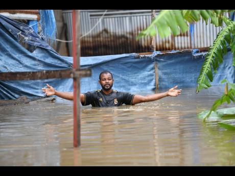
Dwayne McKoy, a resident of Grants Crescent in Hampton Green, Spanish Town, wades through chest-high floodwaters to the rear of his home, from which he operates a furniture workshop. McKoy said that flooding has been a long-standing issue in the Spanish T