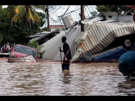 
In this November 6, 2020 file photo, a resident walking through a flooded street looks back at storm damage caused by Hurricane Eta in Planeta, Honduras. 