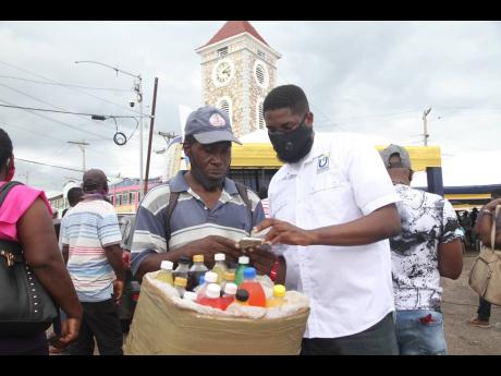 Jason Williams of the Universal Service Fund assists Mark ‘Juici’ Henry to connect to the Internet using the free public Wi-Fi during its launch in May Pen, Clarendon, yesterday.