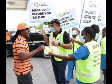 Health and Wellness Minister Dr Christopher Tufton and community health aides hand out COVID-19 sensitisation flyers as they march through the streets of Spanish Town, St Catherine, yesterday to emphasise the importance of masks to containing the coronavir