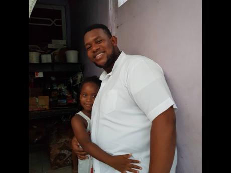 Shemar Miller shares a moment with a young girl after giving care packages to her family in West Kingston