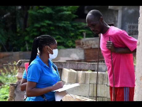 A healthcare worker interacts with a resident of Frazer’s Content, St Catherine, on Saturday as community surveillance was conducted in the community to raise awareness and test persons for the virus. 