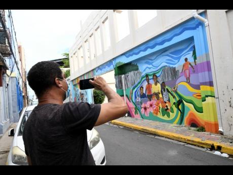 A passer-by captures an image of one of the murals along Water Lane yesterday.