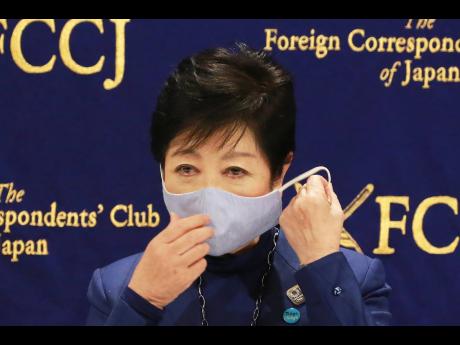 Tokyo Governor Yuriko Koike takes off her mask as she speaks at a news conference in Tokyo, yesterday.