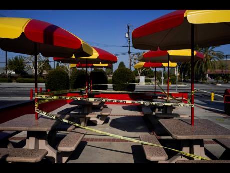 The outdoor dining area of a fast-food restaurant is taped off in Norwalk, California yesterday. Waiters and bartenders are being thrown out of work – again – as governors and local officials shut down indoor dining and drinking establishments to comba