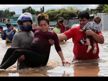A pregnant woman is carried out of an area flooded by water brought by Hurricane Eta in Planeta, Honduras. Thousands of homes were damaged and the infamous gang violence has not relented in Honduras, where some residents said gangs were charging a tax to b