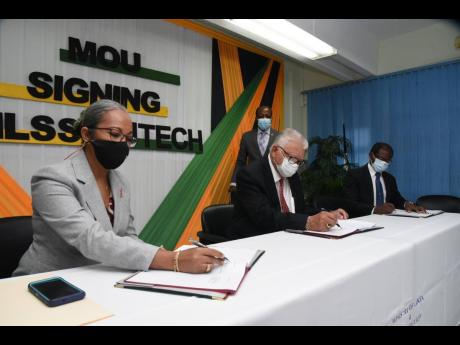 Labour and Social Security Minister Karl Samuda (second left), signs a Memorandum of Understanding to establish partnership with the University of Technolog (UTech) to promote the Labour Market Information System , during a ceremony held at the Ministry’