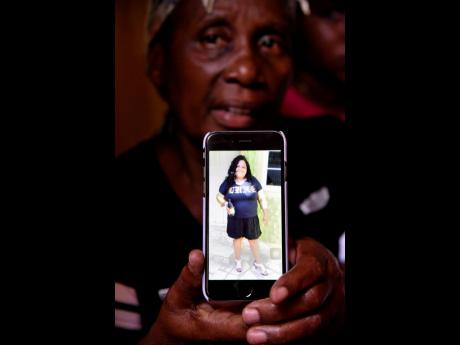 Angella Christine Holmes shows a picture of her daughter, Janice Ellison-Reid, who was shot and killed by gunmen at her home in Thompson Pen, Spanish Town, on Monday afternoon.