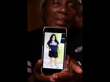 Angella Christine Holmes shows a picture of her daughter, Janice Ellison-Reid, who was shot and killed by gunmen at her home in Thompson Pen, Spanish Town, on Monday afternoon.