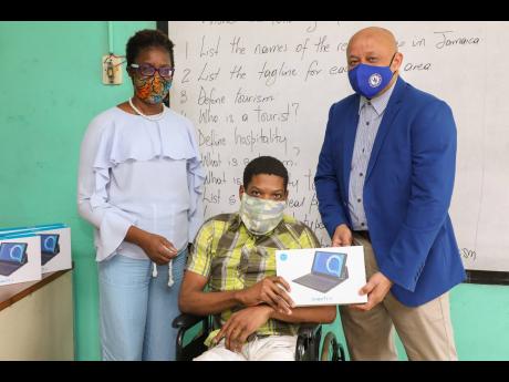 Mark Chisholm (right), Sagicor Foundation director, presents a  tablet to Damarie Thomas (centre), student of the Abilities Foundation, on November 13 at the special education institution. Thomas and four other students received tablets from the Sagicor Fo