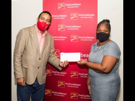Teacher Youlanda Duffus (right), representing the Trench Town Primary School, accepts a cheque from Nigel Holness, managing director of the CIBC FirstCaribbean International Bank, in support of the construction of a tuck shop at the school.  Approximately 