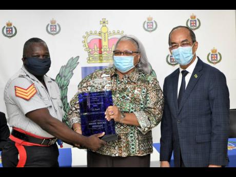 Sergeant Garfield Wallace of the Above Rocks Police Station in St Catherine North accepts the Top Station Award from Jacqueline Hinkson, chairman of the Police (Civilian Oversight) Authority (PCOA), as National Security Minister Dr Horace Chang looks on. T