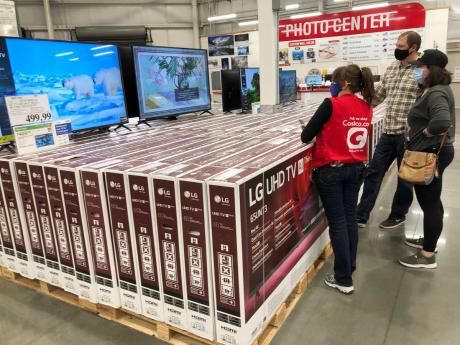 A sales associate helps customers as they consider the purchase of a big-screen television at a Costco warehouse on Wednesday, November 18, in Sheridan, Colorado.