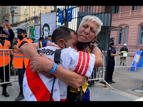 Fans of rival soccer teams Boca Juniors and River Plate embrace as they wait to enter the presidential palace to see the body of Diego Maradona lying in state in Buenos Aires, Argentina, on Thursday.