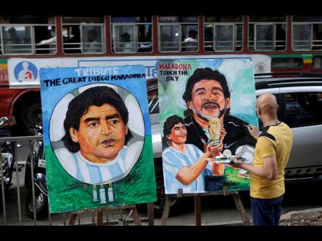 Indian art teacher Sagar Kambli makes a painting of Diego Maradona on a pavement outside his art school in Mumbai, India, Thursday, November 26. The Argentine soccer great died Wednesday aged 60. 