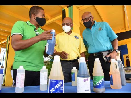 From left: Agriculture Minister Floyd Green; O’Brien Johnson, managing director, St Jago Farm and Hardware Supplies Limited; and Michael Pryce, acting chief technical director in the agriculture ministry, discuss some of the herbicides and fungicides on 