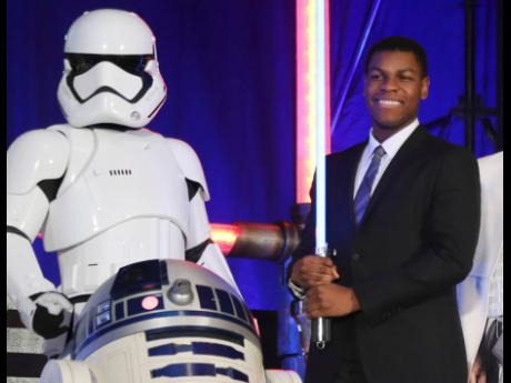 Actor John Boyega (right), poses with Star Wars characters in this December 10,2015 file photograph during the Japan premiere of ‘Star Wars: The Force Awakens’ in Tokyo. 