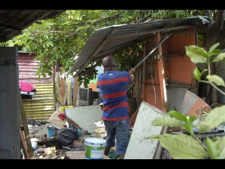 In this October 2016 photo, a man desperately tries to remove a piece of zinc attatched to his former home as residents were on high alert awaiting imminent eviction from the 85 Red Hills Road community.