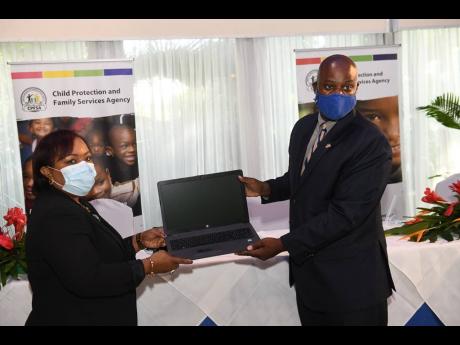 USAID Country Representative Jason Fraser makes a presentation of one of 80 laptops to CEO of the Child Protection and Family Services Agency, Rosalee Gage-Grey, during the opening ceremony of the agency's 2020 Annual Digital Field Services Conference on W