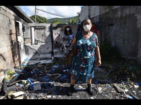 Miriam Lindsay, a triple amputee, stands what remains of her bedroom in the burnt-out shell of her home in Hermitage, near August Town, in St.Andrew. Lindsay lost everything in the fire and is now seeking help to rebuild.