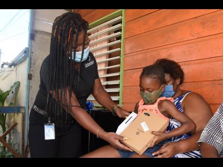 Atl marketing and public relations officer Amalea Jones presents Alia Walker with a new Samsung tablet to assist her with remote learnig. Alia is the daughter of Dwayne and  Staniece Taylor-Walker, a blind couple in Ellerslie Pen, Spanish Town, who have st