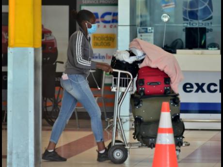 One of the approximately 100 Jamaican citizens arriving at the Norman Manley International Airport on May 31 after a partial reopening of the island’s borders wheels her luggage through the hall.