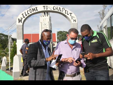 Daryl Vaz (centre), Minister of Science, Energy and Technology; Robert Morgan (right), Member of Parliament, North Clarendon and Daniel Dawes, CEO, Universal Service Fund try the free public Wi-Fi in Chapelton, Clarendon.