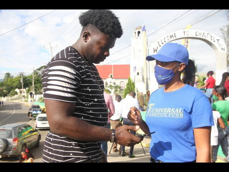 Camera Roberts of Universal Service Fund assists Kenroy Johnson to connect to the free public Wi-Fi in Chapelton.