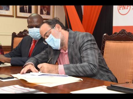 President of the People's National Party, Mark Golding, signs a memorandum of understanding to kick-start the O.T. Fairclough Fund for Party Workers who are in need of monetary assistance. The fund was launched at the PNP's headquarters on Monday. Looking 