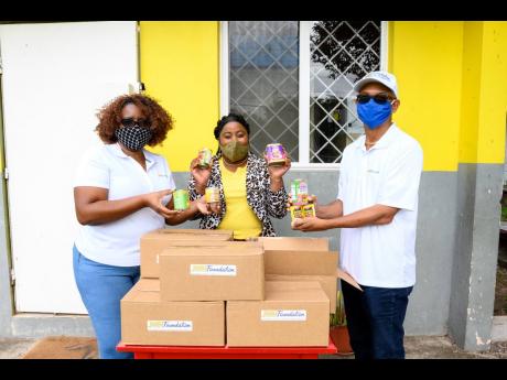 JWNF volunteers Cherly Johnson and Rohan Rohinson present food packages to the principal of York Town Primary School, Francine Swaby.