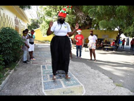 Juliet Holness, member of parliament for East Rural St Andrew, shows her skills in a game of hopscotch on the day that she took part in the presentation of care packages to Harbour View- and Bull Bay-based students.