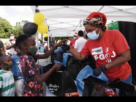 Arlene Miller (right), a member of the Progressive Grocers of Jamaica Limited, helps Darren Crosbale to look through a care package that would better suit him. The handover of care packages to students residing in Harbour View and Bull Bay took place at th