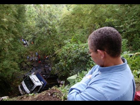 Then Prime Minister Bruce Golding looks down at the truck which went over a precipice the previous night, killing 14 people. Today marks the 12th anniversary of the December 19, 2008, tragedy.