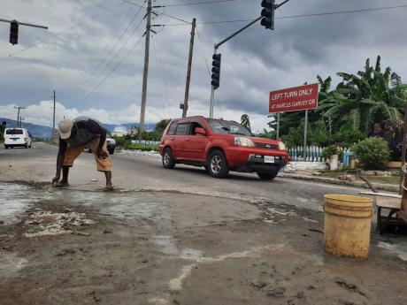 
Shoemaker Almando Bailey (yellow shorts) and friends using cement to patch a section of Chesterfield Drive in Seaview Gardens, St Andrew, last Friday. Motorists had been frequently swerving to potholes along the stretch, increasing the likelihood of colli
