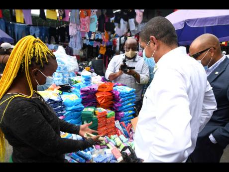 
Mayor of Kingston Delroy Williams (second right) and Robert Hill (right), CEO of the Kingston and St Andrew Municipal Corporation, don masks as they engage with a vendor while touring sections of downtown Kingston to observe the level of compliance to COV