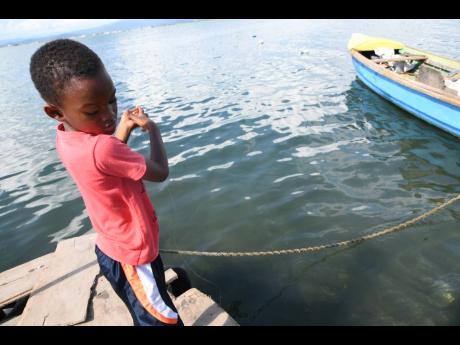 Adonai Smith line-fishing in Port Royal on Tuesday. Fisherfolk blame dwindling catch on dredging and the anchoring of ships in sensitive areas.