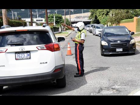 A policeman directs traffic in the vicinity of PriceSmart wholesale club in St Andrew. The community of Valentine Gardens has been affected by traffic trauma.