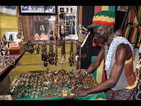 Glenford Bennett shows off some of his craft items inside his 23 Third Street shop in Trench Town, Kingston.