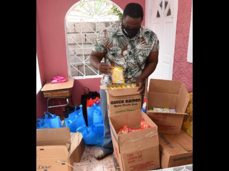 Pastor Junior White packaging food items, toileteries and sanitisers in bags for the elderly in Allman Town.