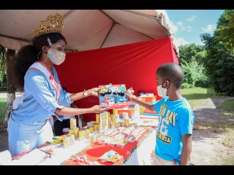 Nicola Thomas, Miss Jamaica United Nations, hands Raheem Whittaker, who has sickle-cell disease, a toy he chose at the fourth annual Shak's Hope Retreat for Families Fighting Sickle-Cell Disease. The event was held at St Margaret’s Church in Kingston. 