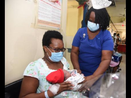 Elise Fairweather Blackwood, director of nursing services at Victoria Jubilee Hospital, hands Tracy Ann Jackson her baby, Magnus Alphonso Jackson, who was born on Christmas morning.