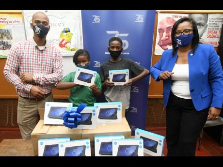 Corporate Services and Client Experience Manager at Kingston Wharves Limited (KWL), Simone Murdock (right), presents gifts of tablets to children of St Anne’s Primary School in west Kingston. Accepting are Principal Omar Thomas and two of the beneficiary