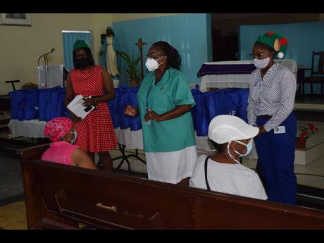 SAJ’s occupational health officer Nurse Deanmarie White (standing centre) gives useful advice on COVID-19 prevention to senior citizens of Greenwich Town during the Shipping Association of Jamaica’s Christmas Treat held recently at the Holy Name of Jes