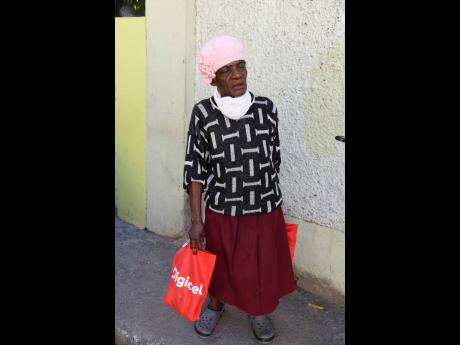 Hellen Harrison stops to speak with The Gleaner as she makes her way home with care packages in August Town, St Andrew, on New Year’s Eve.