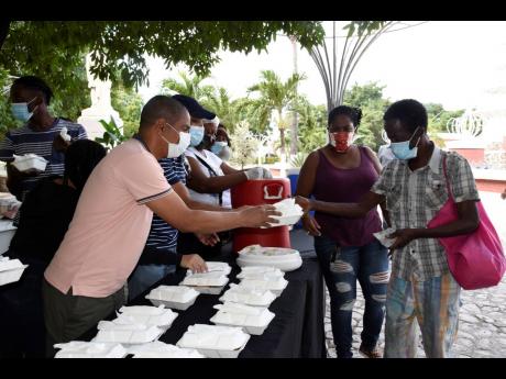 Kingston Mayor Delroy Williams handing out food to indigent persons at St William Grant Park in downtown Kingston, a New Year’s Day tradition.